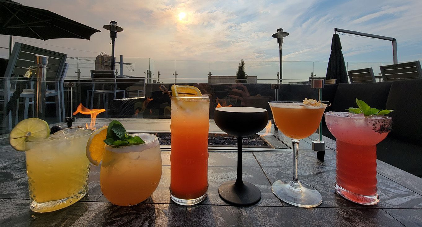 Rooftop fireplace with 6 various cocktails and garnishes.